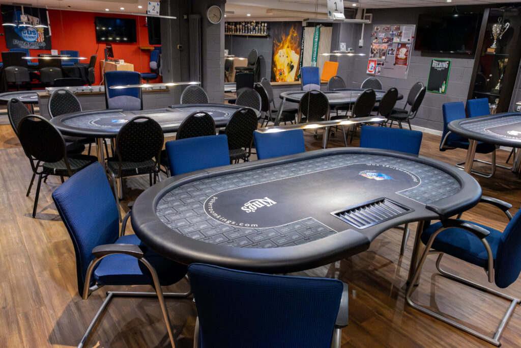 Blick über mehrere Pokertische im Spielraum, im Hintergrund die Pokalvitrine